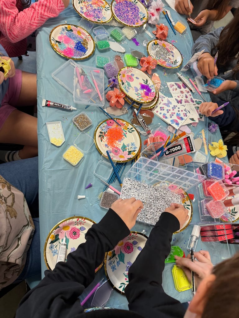 Children gathered around a table decorating paper plates with colorful stickers, flowers, and craft materials during a group activity
